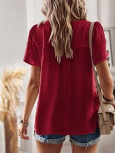 Detail view of the back of a red short-sleeve shirt with subtle polka dot texture