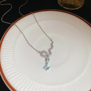 Macro shot of a silver snake pendant with white zircons and a round diamond on a tray