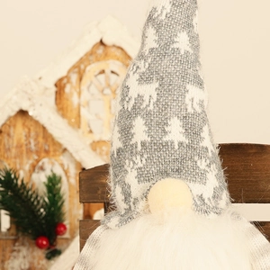 Gros plan d'un gnome de Noël lumineux avec un bonnet tricoté gris aux motifs d'élans