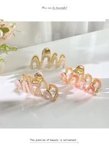 Detailed set of three wavy acetate hair claws in cream, pink, and peach colors