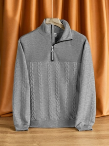 Dettaglio pullover grigio con zip, evidenziando maglia a nido d'ape e trecce su maniche