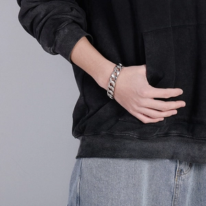 Gros plan d'un bracelet gourmette argenté porté par un mannequin en style streetwear