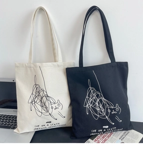 Detail of minimalist canvas tote bags featuring cute abstract cat graffiti and text