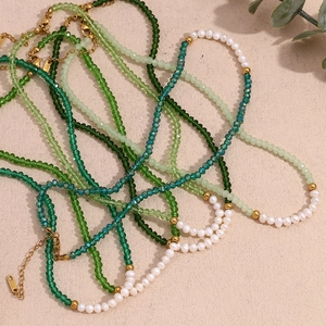 Detail of green crystal beads and freshwater pearls on golden beaded necklaces