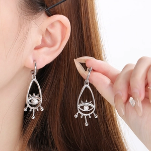 Detailed view of silver evil eye dangle earring with shell inlay and a white pearl accent