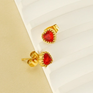 Close-up of heart-shaped gold studs with red zircon and detailed beaded metal edges