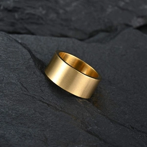 Detail of 10mm matte brushed gold titanium steel ring on black rock texture