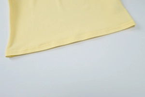Dettaglio dell'orlo a doppia cucitura di un gilet in maglia aderente giallo chiaro