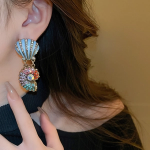 Close-up of model wearing colorful shell earrings with crystal stones and enamel