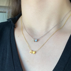 Close-up of gold and silver S925 necklaces with B-letter and heart pendants on model