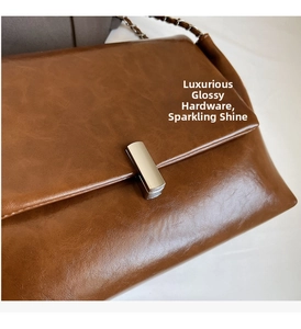 Close-up of bright metal buckle and glossy brown oil wax leather texture on a tote bag