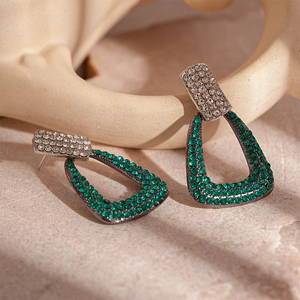 Detailed macro view of geometric earrings with emerald green and white zircons