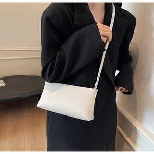 Detailed close-up of a white rectangular leather baguette bag with thin shoulder strap