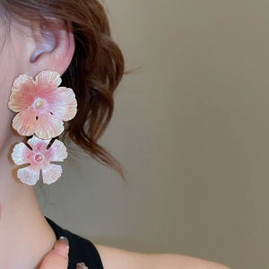 Close-up of pink gradient double flower earrings with delicate pearl accents on a model