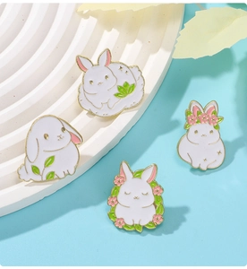 Close-up of four cute white rabbit enamel pins with gold edges on display stand