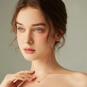 Elegant gold bean pendant necklace on minimalist chain worn by a female model