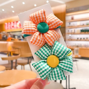 Detail of cute fabric flower hair ties with orange and green checkered floral patterns