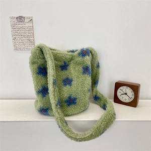 Detail of light green plush faux shearling bucket bag with blue floral patterns