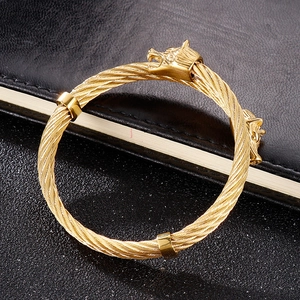Detail of golden lion head torque bangle with twisted cable texture on black background
