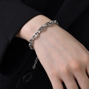 Detail of S925 sterling silver anchor link bracelet with logo charm worn on wrist