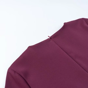 Détail de la fermeture éclair invisible et du col rond sur une robe courte bordeaux