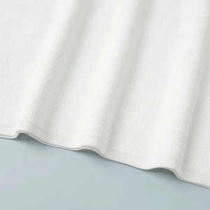 Detailed macro view of white ribbed knit fabric texture with elastic hem finish