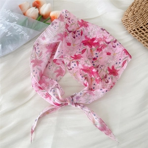 Detail of pink floral diamond silk scarf tied as a headband on white background