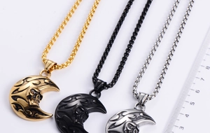 Detailed view of punk crescent moon skull pendants in gold, black, and silver with scale ruler