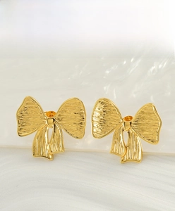 Détail de boucles d'oreilles nœuds papillon en or 18K avec texture en métal brossé