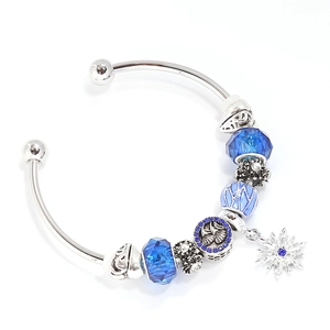 Macro detail of silver charm bracelet with ice blue faceted crystals and snowflake pendant