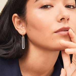 Close-up of dual-tone 18K gold and silver geometric long earrings worn by a model