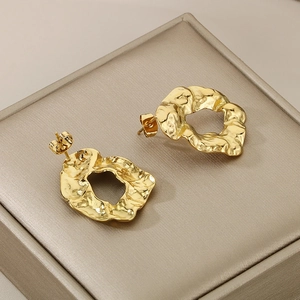 Irregular textured gold hoop earrings with a modern hammered surface on jewelry box