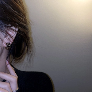 Détail de boucles d'oreilles asymétriques en forme de C avec motif grec géométrique
