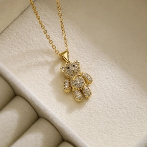 Squisita collana con ciondolo a orsetto in oro e zirconi scintillanti su velluto beige