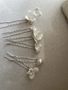 Close-up of elegant bridal hair pins featuring white ceramic flowers and faux pearls