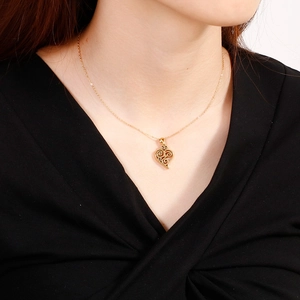 Close-up of gold hollow heart pendant necklace worn by a model on a black outfit