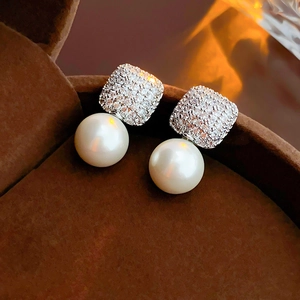 Macro shot of silver square zircon earrings with white pearls in a brown jewelry box