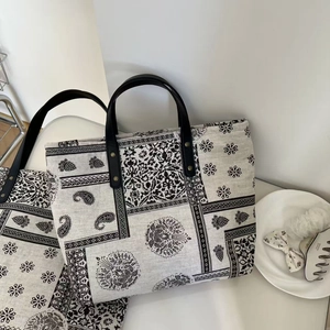 Detailed view of paisley canvas tote bag with leather handles and metal rivet reinforcement
