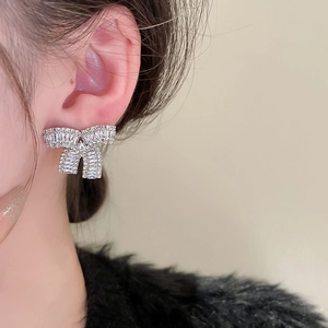 Dettaglio di orecchini a fiocco in argento con zirconi indossati per uno stile raffinato