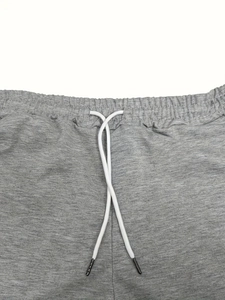 Gros plan sur la taille élastique avec cordon blanc du short de sport en coton gris