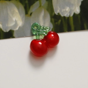 Macro view of bright red cherry pendant charm with green leaves for DIY jewelry making