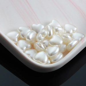 Lustrous cream heart-shaped faux pearls for DIY jewelry making on marble tray