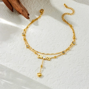 Gold double-layer MOM anklet with heart pendants and rhinestones on white surface