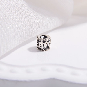 Macro détaillée d'une perle barillet en argent S925 avec gravures bouddhistes ajourées