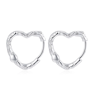 Minimalist silver heart-shaped earrings with irregular textured finish on white background