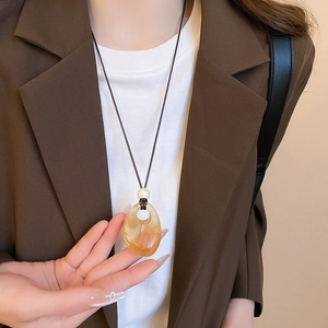 Detail of amber marble pendant necklace with white bead on elegant dark blazer
