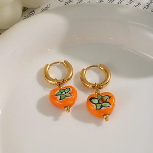 Gros plan boucles d'oreilles créoles dorées avec coeurs orange et motif floral vert