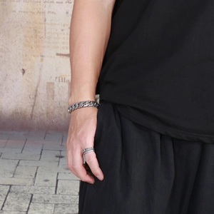 Close-up of vintage silver Cuban link bracelet and twisted rope ring on model wrist