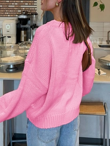 Back view of a casual loose pink knitted sweater for women in a cafe setting