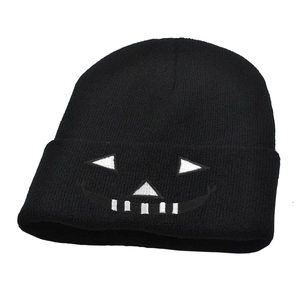 Close-up of white Jack-o'-lantern embroidery on a black knitted Halloween beanie